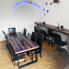 Un salón de conferencias con una larga mesa, sillas, un escritorio y una estantería en la pared.