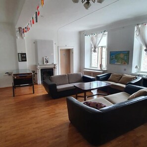 Una sala de estar con chimenea, sofás, una mesa de centro y una mesa de comedor.