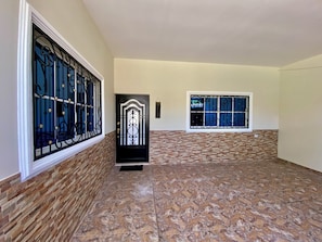 A hallway with a black door, a window with metal bars, and a welcome sign.