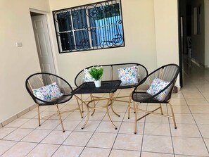 A dining area with a table and four chairs, a potted plant, and a window with decorative bars.