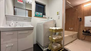 A hotel bathroom with a sink, mirror, towel rack, and shower area.