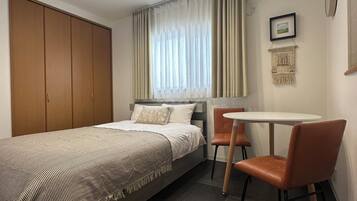 A bedroom with a bed, a desk, and chairs.