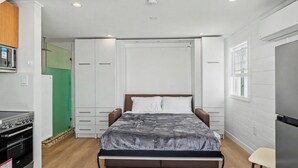 Ein Schlafzimmer mit Bett, Kleiderschrank und einer Küchenzeile.