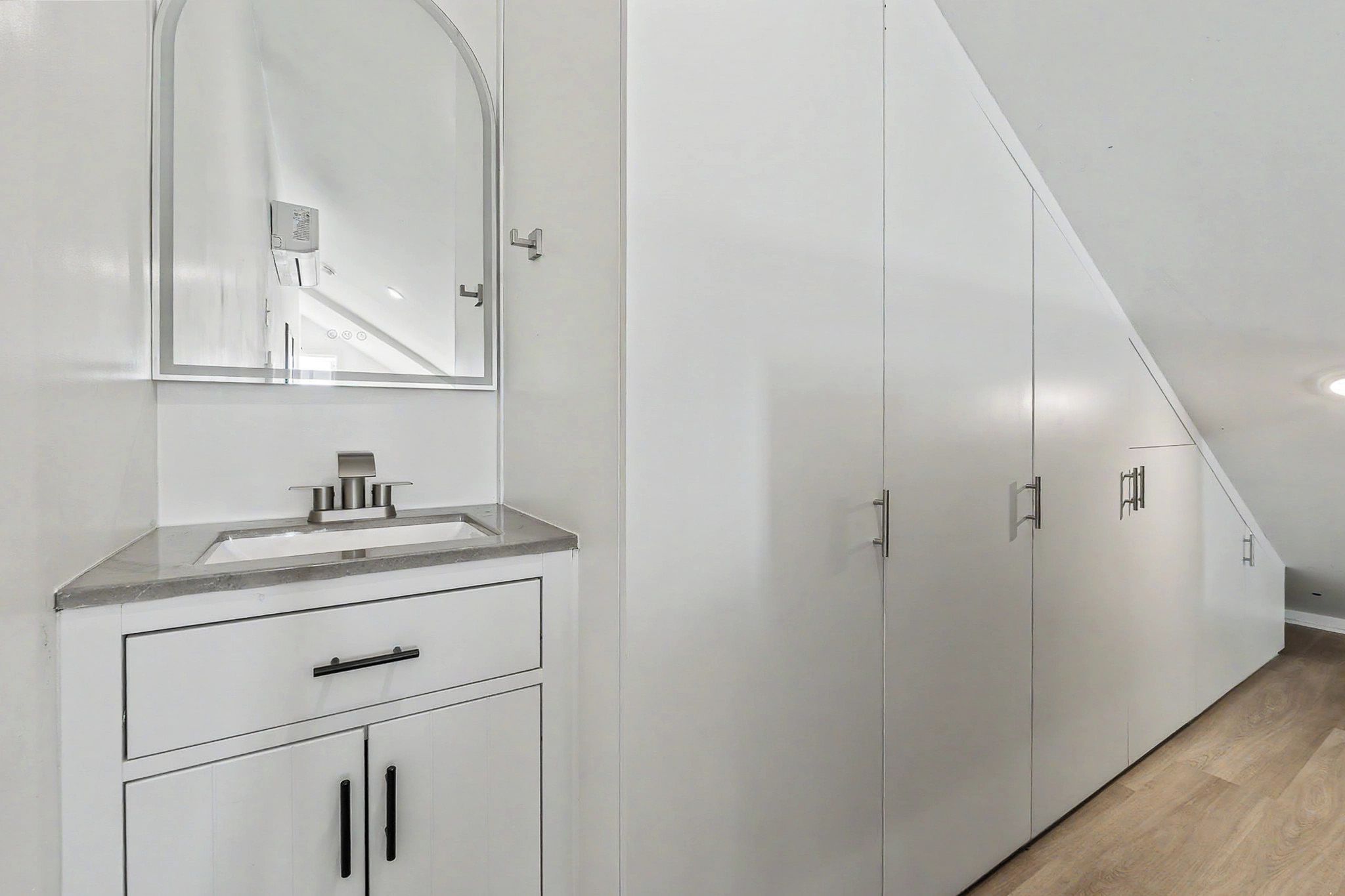 Une salle de bain moderne avec un grand miroir, un lavabo et des meubles de rangement.