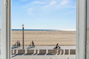 A beach view from a covered walkway with a lamp post and a clear sky. - On the Boardwalk Loft with Ocean Front Views (Santa Monica)