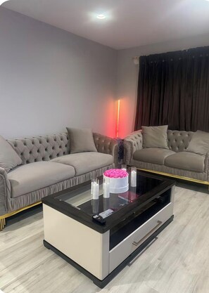 A modern living room with two sofas, a glass coffee table, and a decorative cake.
