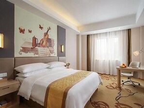 A hotel room with a bed, a desk, a chair, a lamp, and a large wall mural. - Vienna International Hotel (Nanjing)