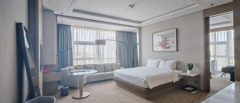 Habitación de hotel moderna con cama, mesita de noche, lámpara y vistas al exterior.