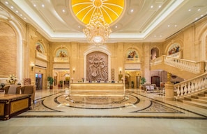 A grand lobby with a central reception desk, a large chandelier, and a grand staircase. - Vienna International Hotel (Fuzhou)