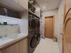A compact laundry area with a sink, two washing machines, and a door leading to another room. - Vienna International Hotel (Fuzhou)