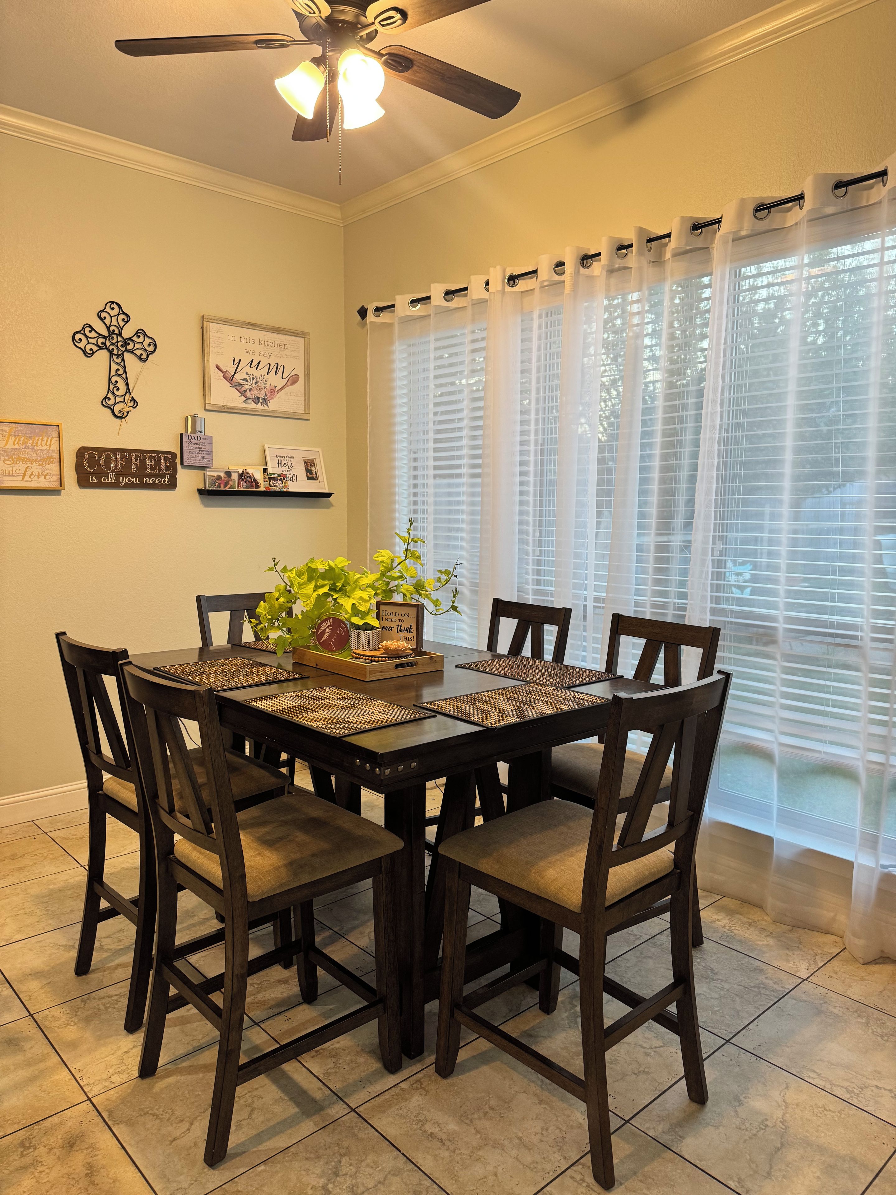 A dining area with a dark wooden table, four chairs, and a ceiling fan.