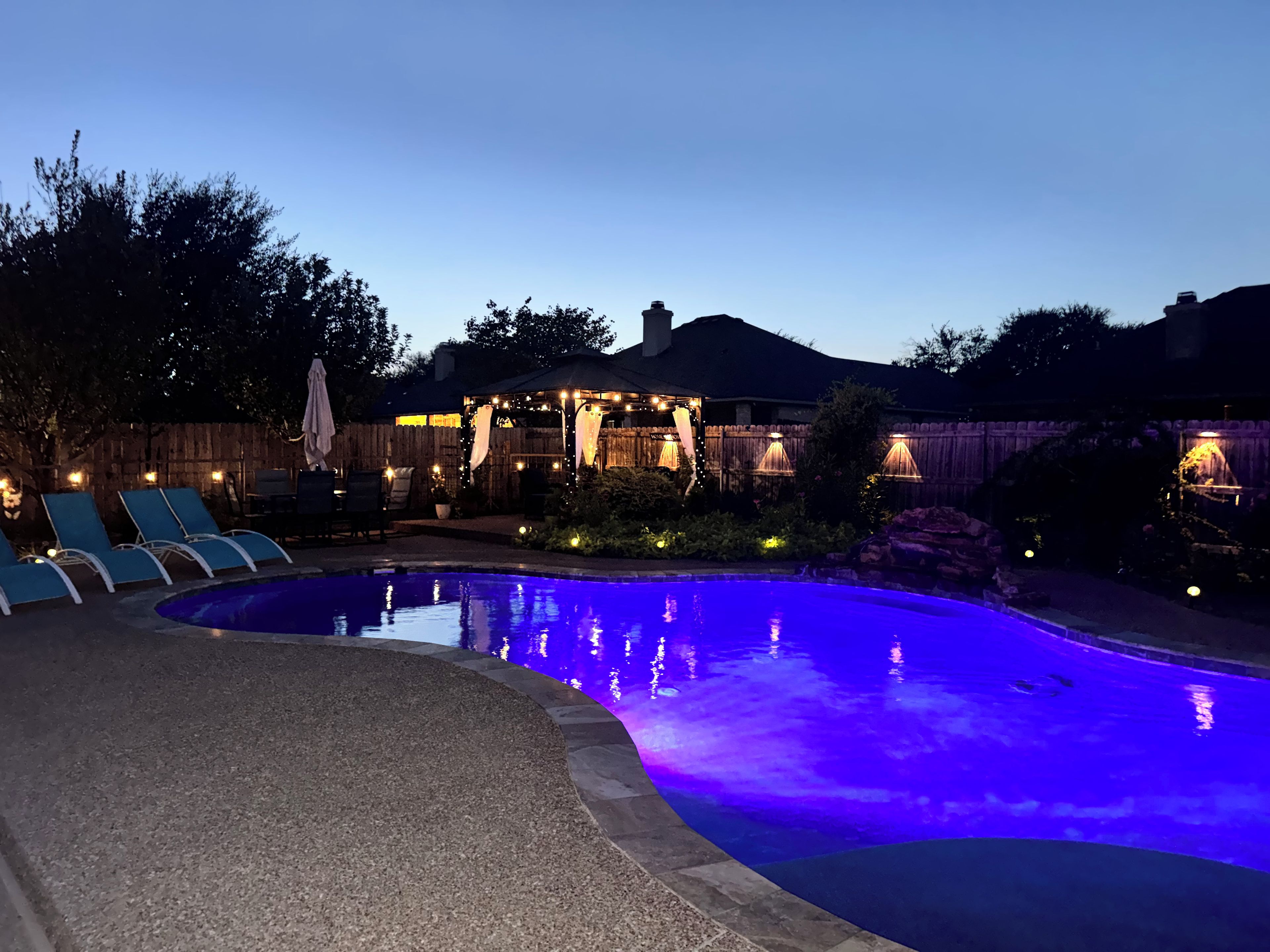 A swimming pool with a curved edge and a pebble-lined deck.