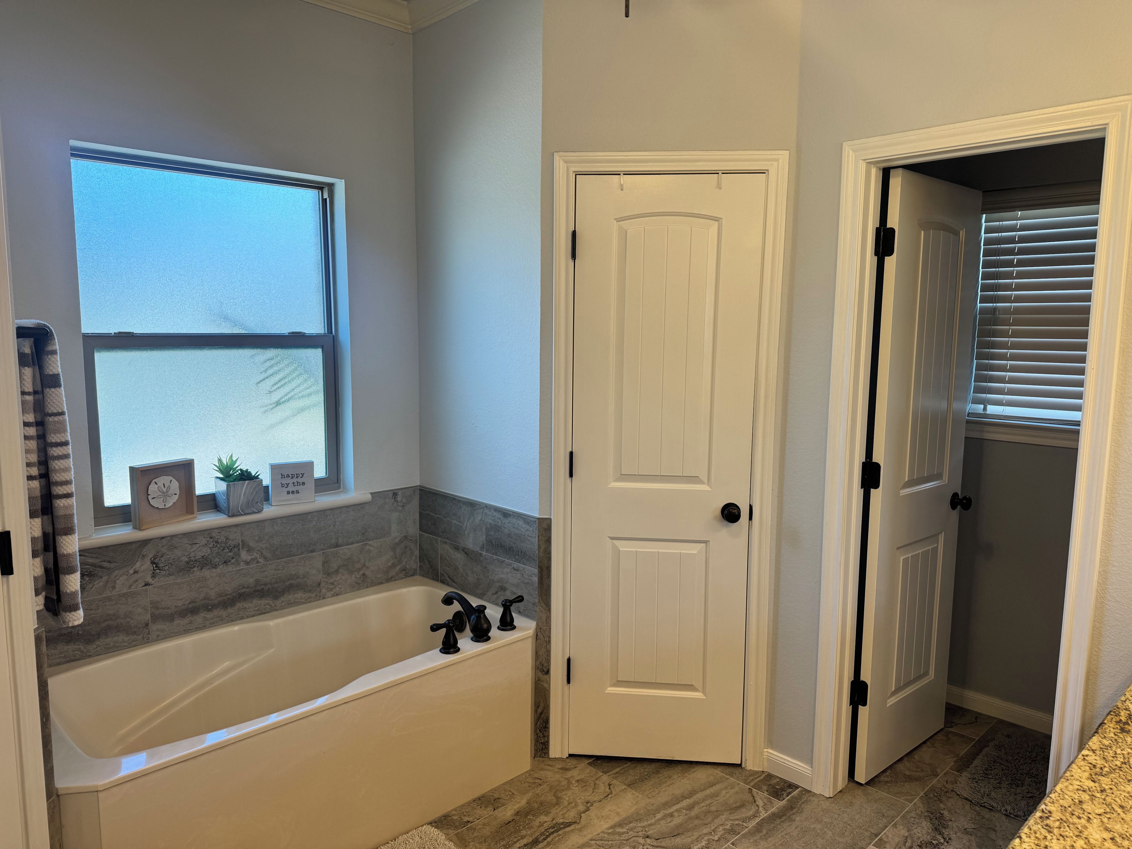 A bathroom with a bathtub, a window, and a door.