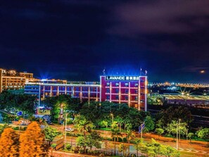 Un hotel con un letrero llamativo, rodeado de follaje y una calle bien iluminada durante la noche.