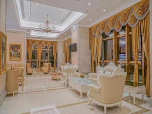 A luxurious living room with ornate furniture, a chandelier, and large windows with curtains. - Vienna International Hotel (Chongqing)