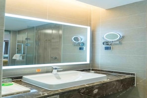 A modern bathroom with a large mirror, a white sink, and two illuminated mirrors on the wall. - Vienna International Hotel (Chongqing)
