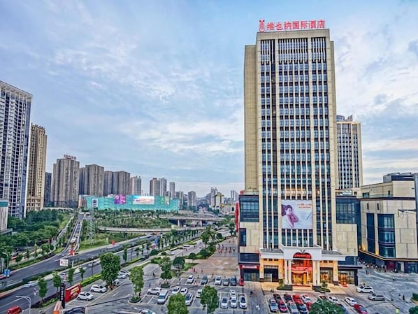 A high-rise building with multiple floors, surrounded by other tall buildings, and a busy street with cars and pedestrians. - Vienna International Hotel (Chongqing)