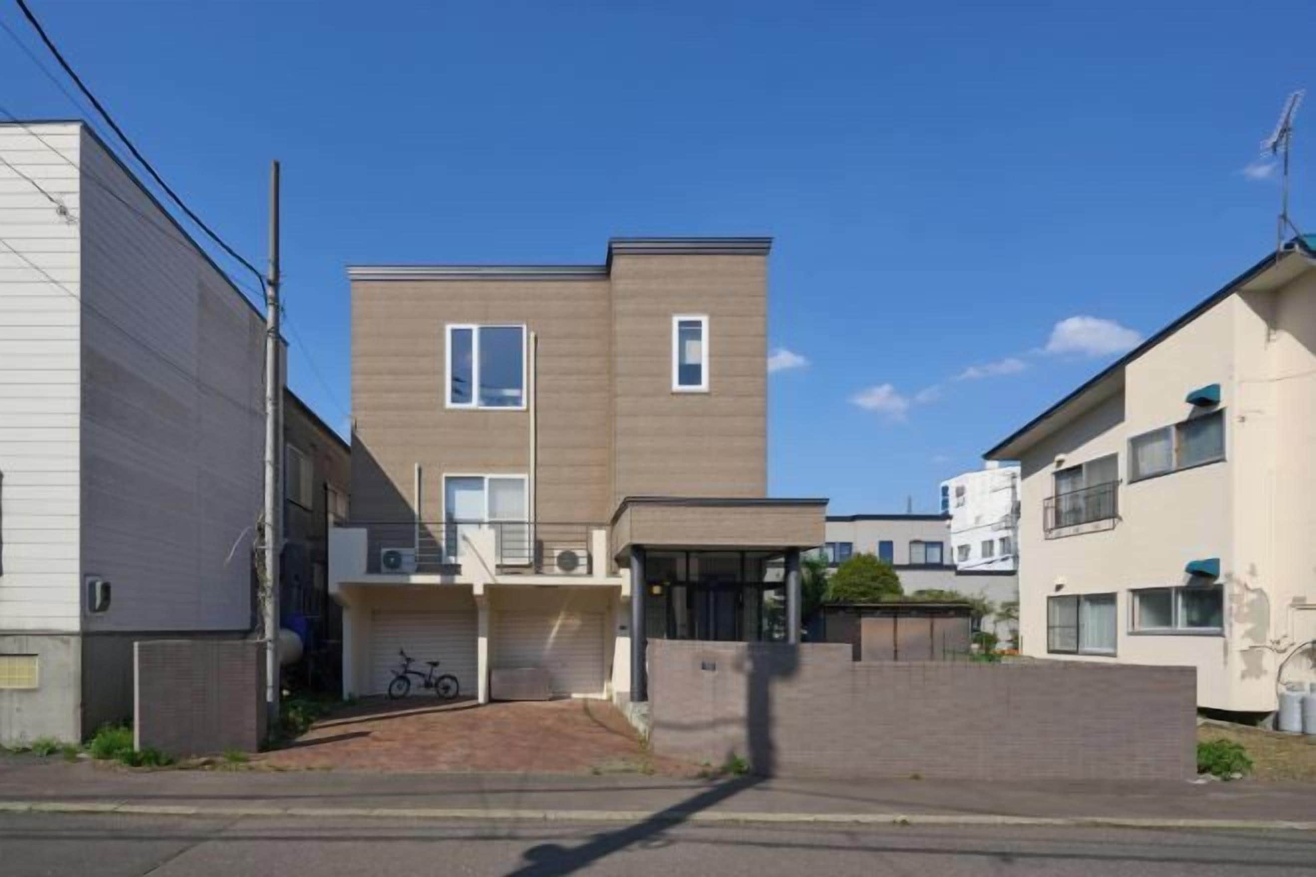 A two-story residential building with a garage, a bicycle, and a small front porch.
