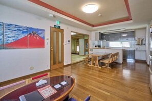 A hotel room with a wooden floor, a dining area with a table and chairs, and a kitchen area with cabinets and a refrigerator. - Sapporo Vacation Home B&B (Sapporo)