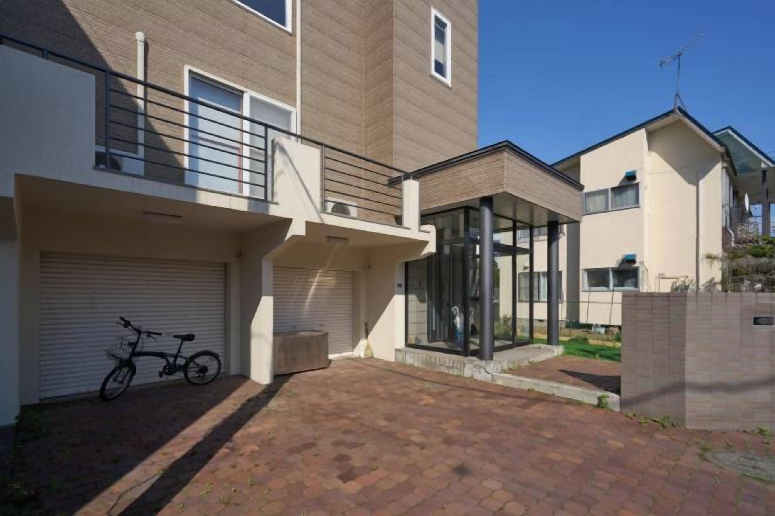 A residential building with a garage, a bicycle, and a glass-enclosed patio area.