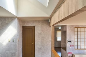 A room with a wooden door, a window with blinds, a wall-mounted air conditioning unit, and a ceiling with skylights. - Sapporo Vacation Home B&B (Sapporo)