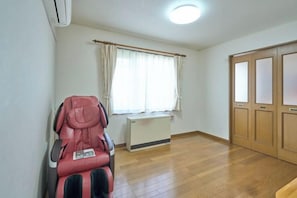 A room with a massage chair, a window with curtains, and a wooden wardrobe. - Sapporo Vacation Home B&B (Sapporo)