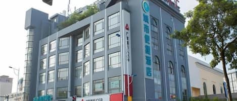 A multi-story building with signage for a convenience store and a health club.