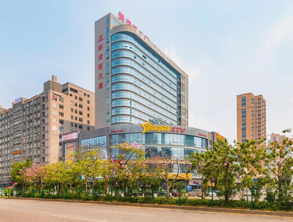 A modern hotel with a curved facade, multiple floors, and a prominent sign. - Lavande Hotel (Dongguan)