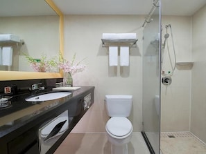 A modern bathroom with a glass-enclosed shower, a white toilet, and a black sink with a mirror above. - Vienna Hotel (Dongguan)