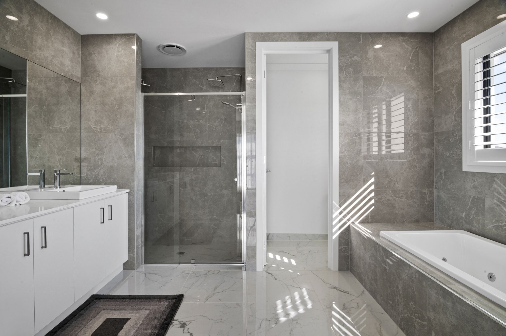 A modern bathroom with a walk-in shower, a bathtub, and a large mirror.