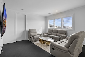 Een moderne woonkamer met een bank, fauteuils en een salontafel.