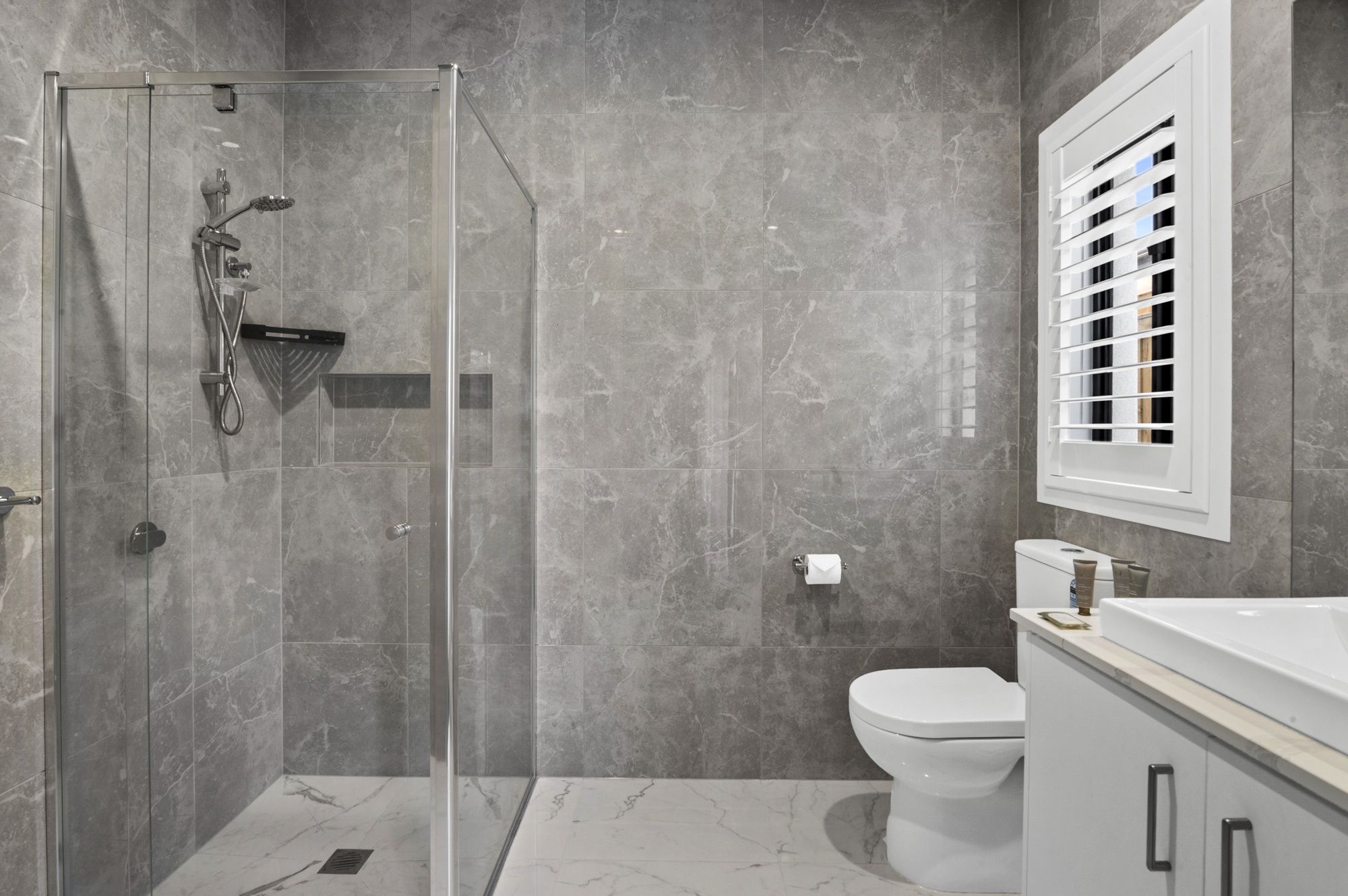 Une salle de bain moderne avec une douche à parois de verre, des toilettes et un meuble-lavabo avec un miroir.