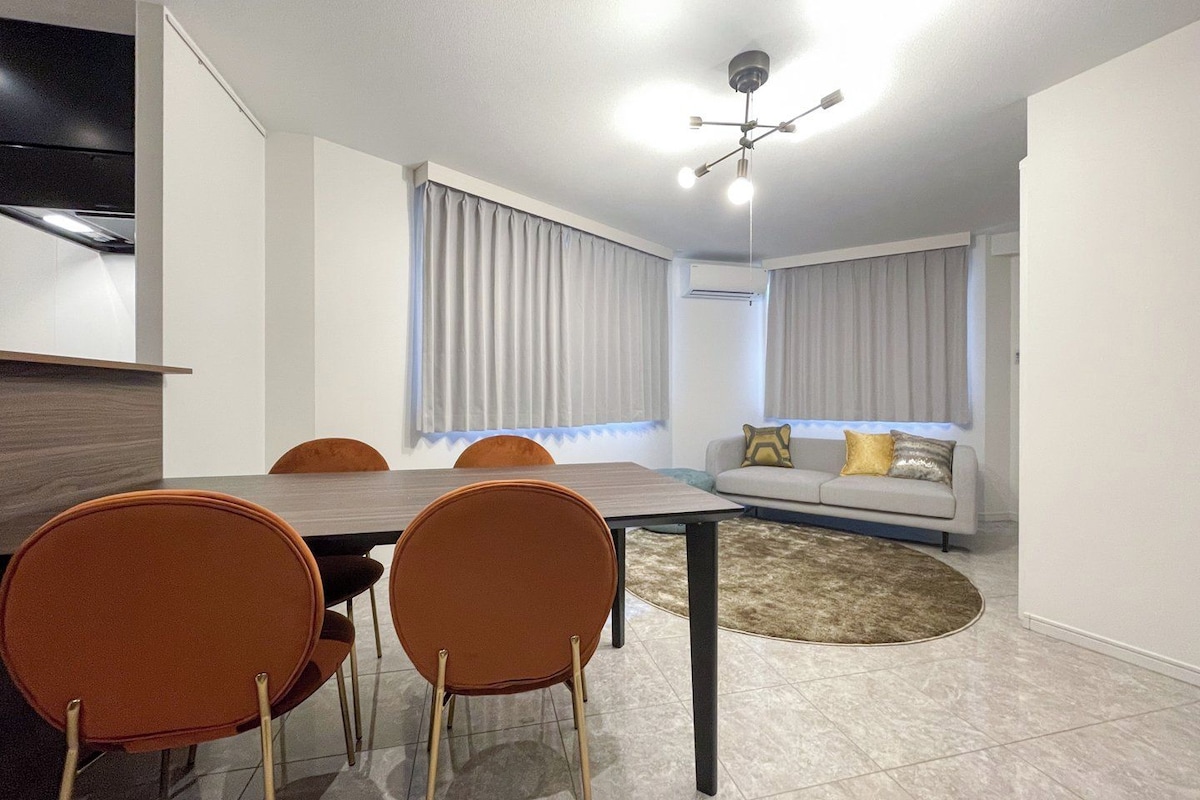 Ein modernes Wohnzimmer mit Essbereich, inklusive Tisch, Stühlen und einer Couch mit Kissen.