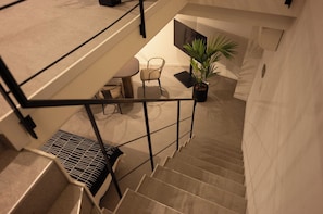 Eine Treppe mit Metallgeländer, einem Blumentopf und einer Sitzgruppe mit Tisch und Stühlen.