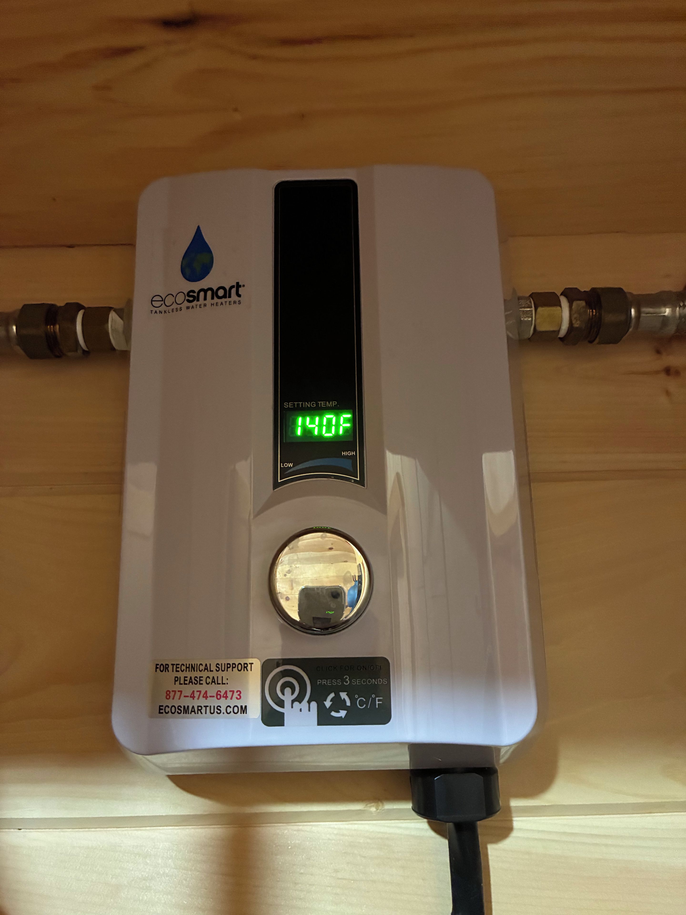 Ein Durchlauferhitzer mit digitaler Anzeige, eingestellt auf 60 Grad Celsius, einem Stromkabel und einem Hinweis für technischen Support.