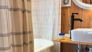A bathroom with a bathtub, a sink, and a mirror. There are storage containers and a shower curtain.
