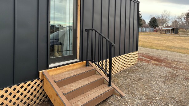 A modern building with a large window, a wooden staircase, and a metal railing.