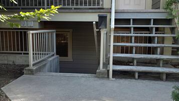 Un edificio de dos pisos con una entrada principal, un pequeño porche y una serie de escalones de hormigón que conducen a la puerta.
