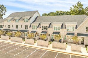 A multi-story building with a brick facade, multiple windows, and a parking lot in front.