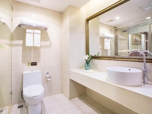 A bathroom with a toilet, sink, and mirror. - Vienna Hotel (Chengdu)