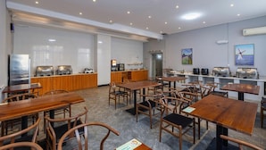 A restaurant with multiple tables and chairs, a kitchen area, and a wall-mounted air conditioning unit. - Lavande Hotel (Ganzhou)