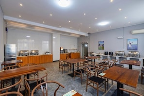 A restaurant with multiple tables and chairs, a kitchen area, and a wall-mounted air conditioning unit. - Lavande Hotel (Ganzhou)