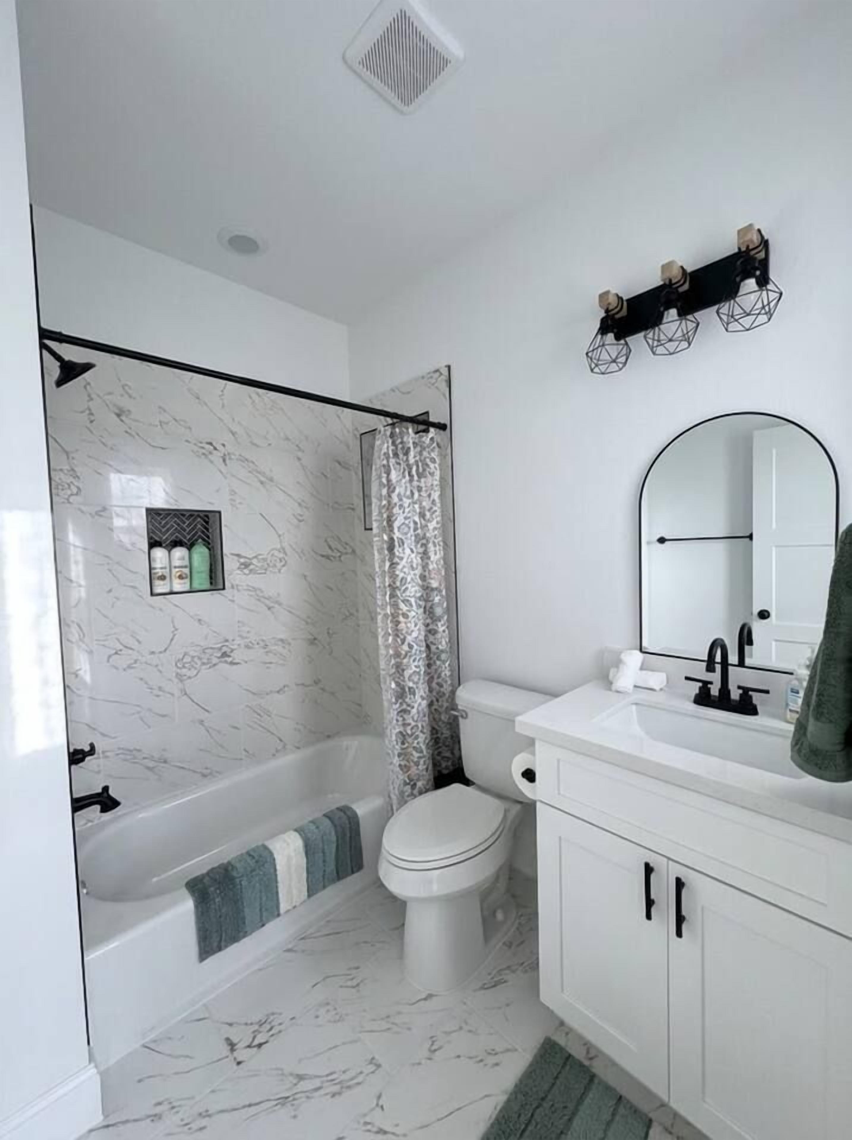A bathroom with a bathtub, toilet, and vanity with a mirror.