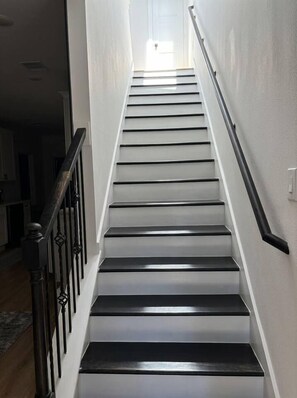 A staircase with a handrail on the right, leading to an upper floor. - Modern 2BR Townhome | Medical Center • NRG • Hobby (Houston)