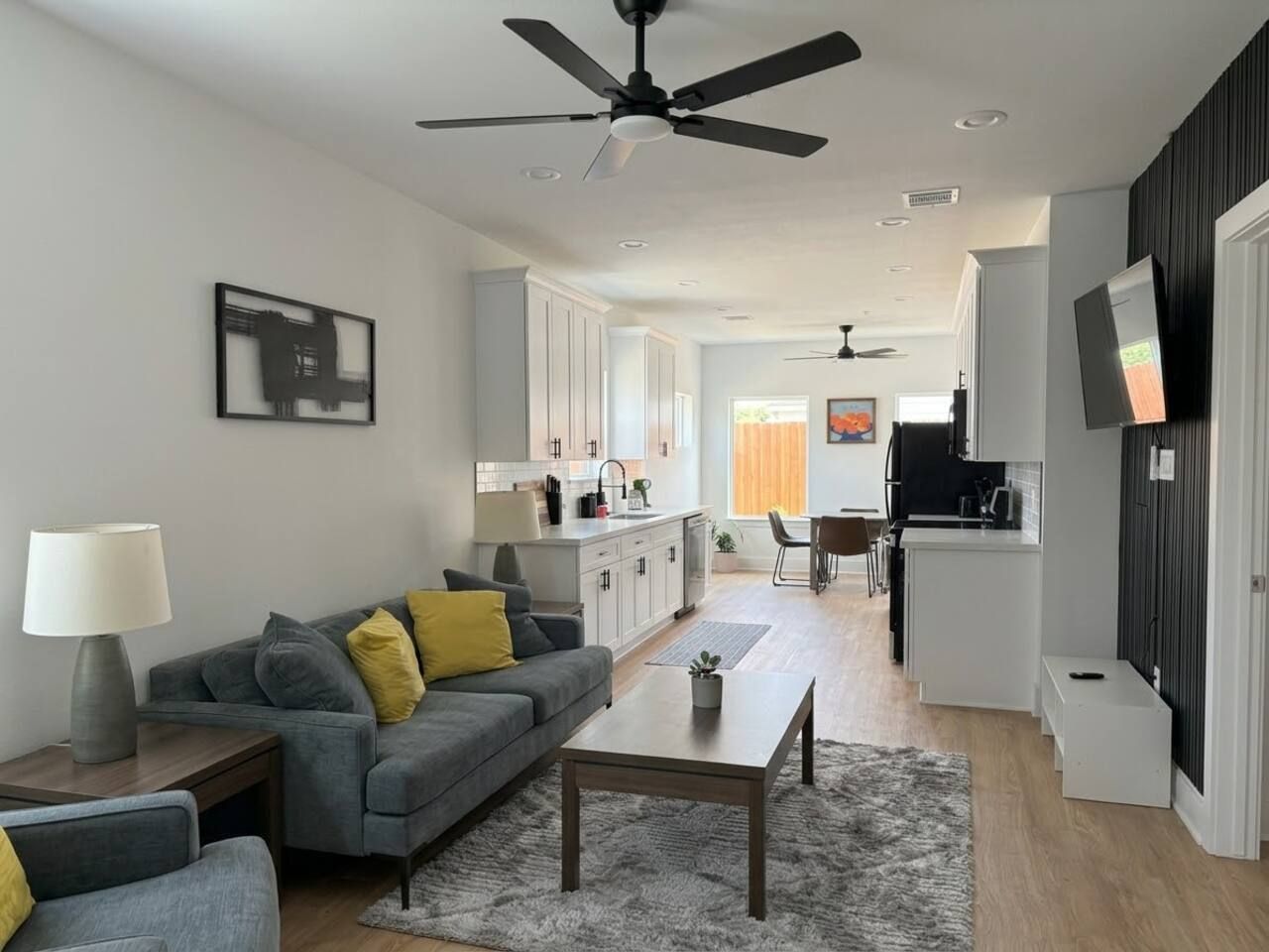Ein modernes Wohnzimmer mit einem grauen Sofa, einem Couchtisch und einem Deckenventilator.