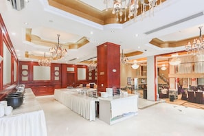 A spacious hotel lobby with a reception desk, a buffet area, and a staircase leading to another floor. - Vienna International Hotel (Ningbo)