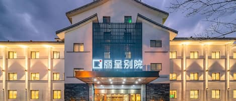 Um hotel com fachada moderna, entrada imponente e uma placa em idioma estrangeiro.