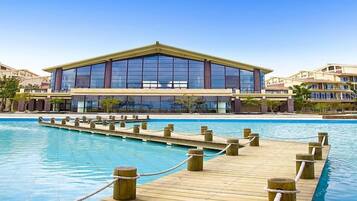 A hotel with a large pool and a wooden deck.
