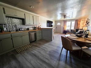 A kitchen with a dining area, wooden flooring, and a ceiling fan.
