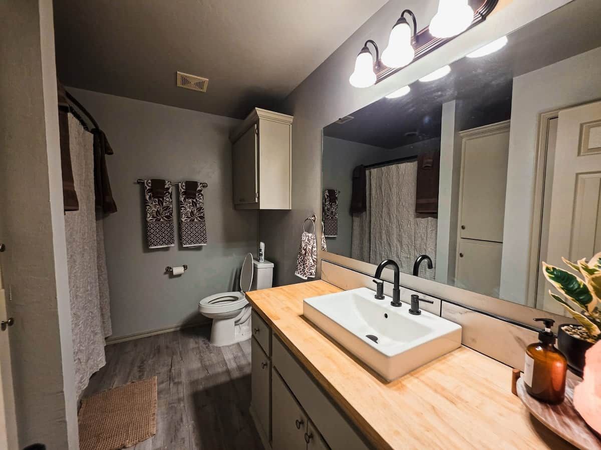 A bathroom with a white sink, a mirror, and a toilet.
